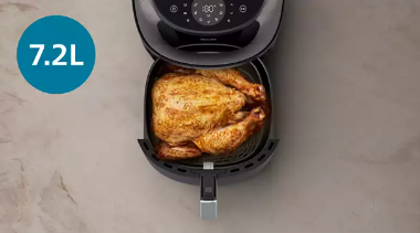 Whole roast chicken in the open basket of the 7.2 L Philips Airfryer