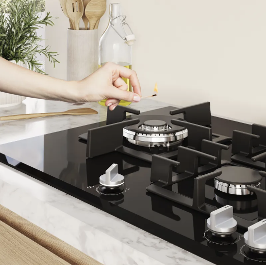 Hand lighting a gas burner on a black glass hob with a match